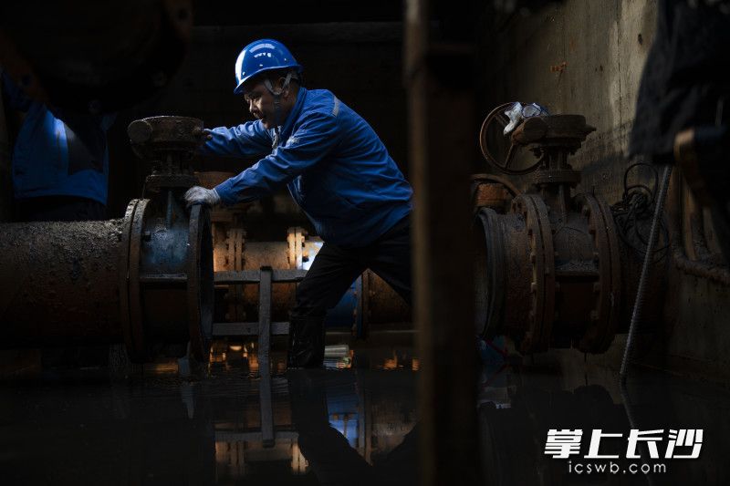 在长沙水业集团长善垸水质净化厂，薛印在一处地下管道接口进行维修检查。
