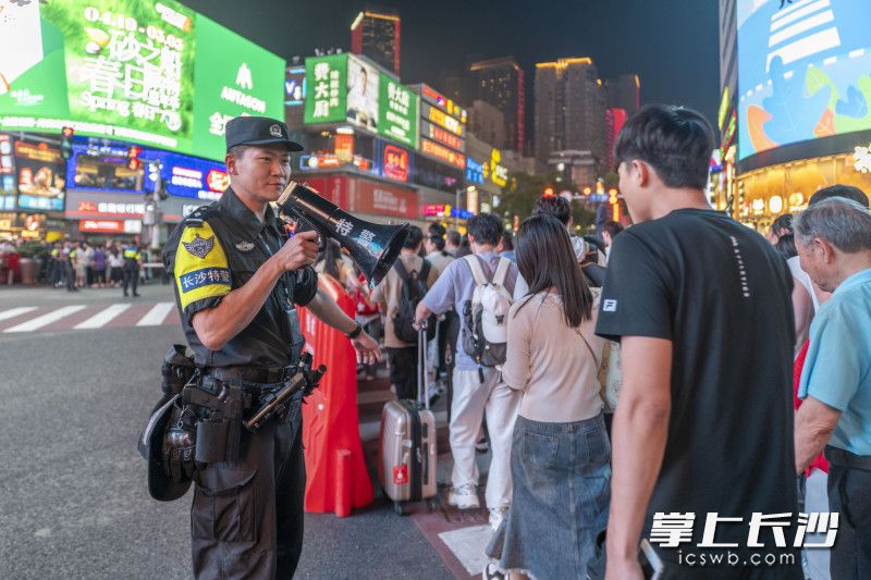 5月1日晚，执勤特巡警手持喇叭疏导摩肩接踵的游客。