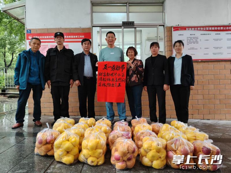 “五一”前夕，周松林（左四）、潘乐玲（左五）夫妇给物业公司全部28名工作人员送去了苹果。  均为长沙晚报通讯员刘淮摄