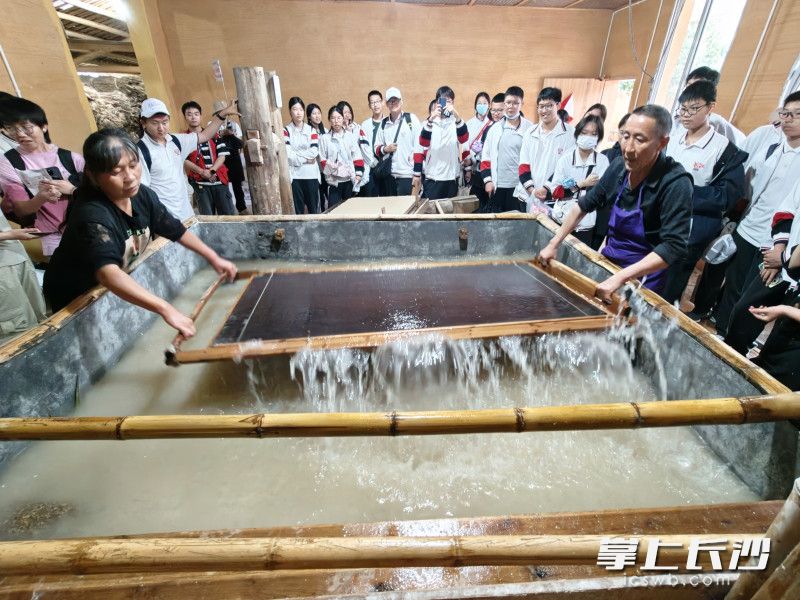 参观了解浏阳手工竹纸制作工坊，学生们与手艺人赵尚兵共同抄纸。