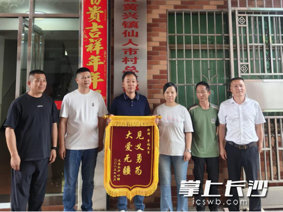 获救家庭将印有“见义勇为 大爱无疆”的锦旗交到施救者手中。