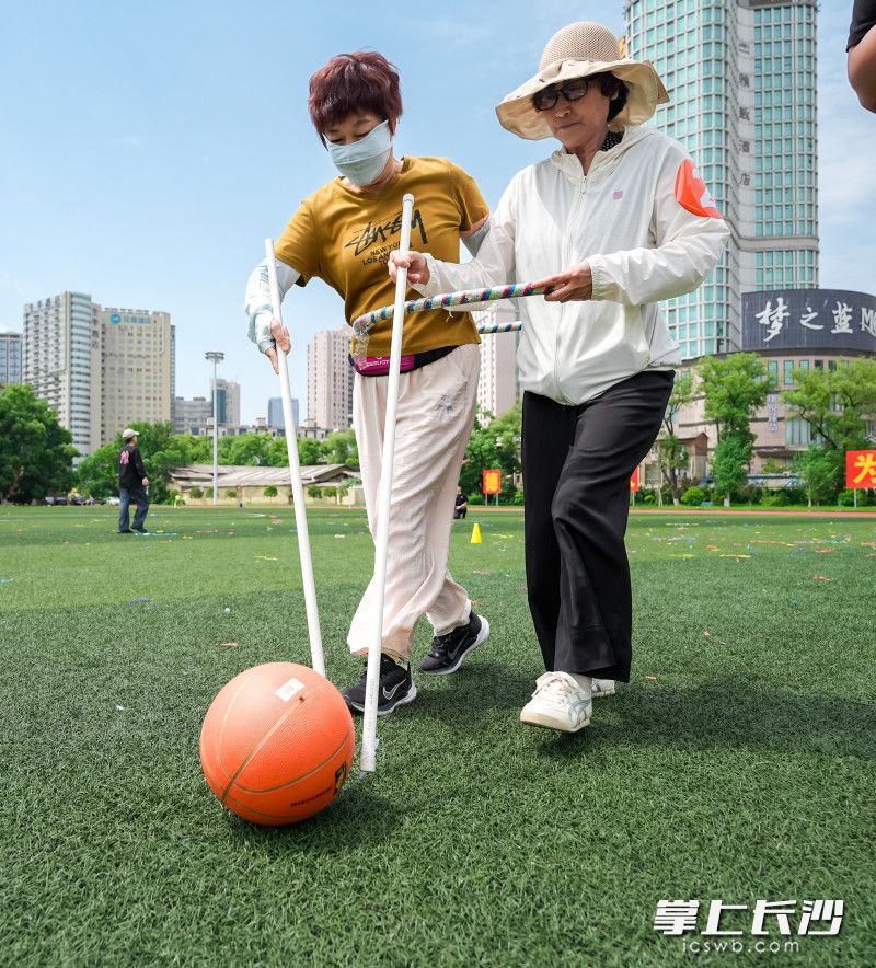 “赶猪跑”赛道更成了欢乐剧场——老人们两人一组，手握木杆“驱赶”篮球。