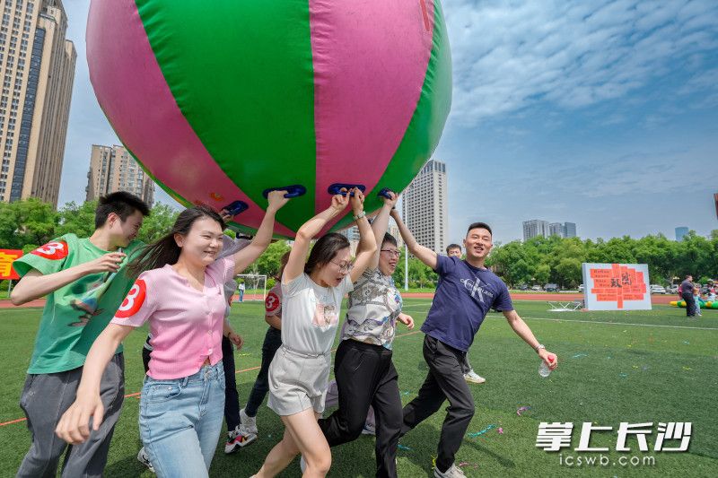 “鸿运彩球”项目中，8人团队合力托起巨型充气球，喊着整齐的“一二、一二”口号向前冲刺。