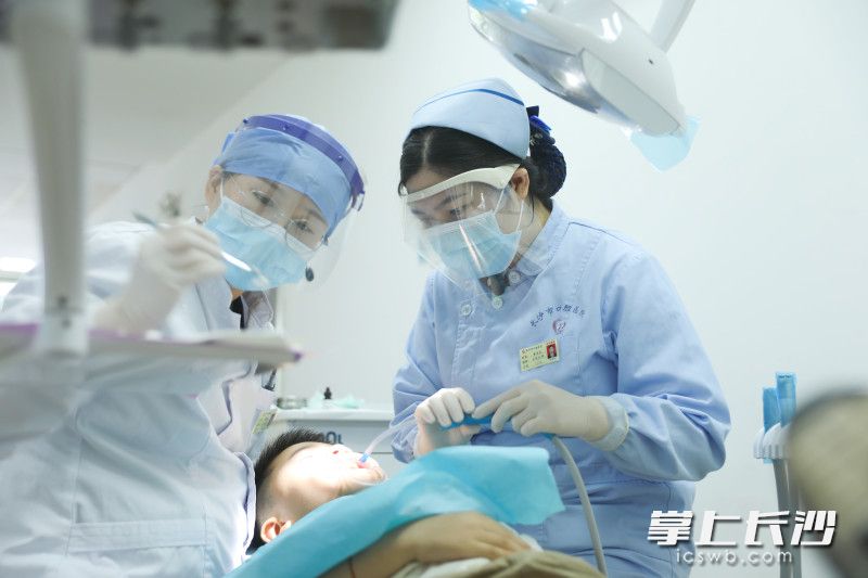 长沙市口腔医院友谊路院牙周黏膜科护士长、主管护师章作号（右）正和医生配合为小患者进行口腔手术。