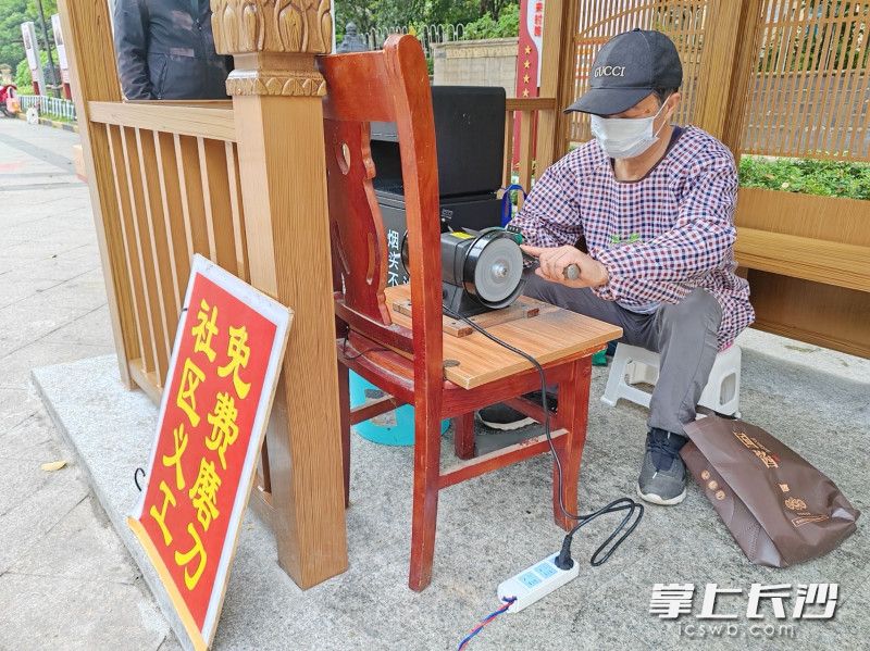 贺建林在“磨刀爱心摊位”帮居民磨刀。 东恒社区供图