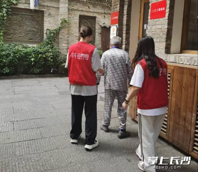 志愿者帮扶行动不便的老人。