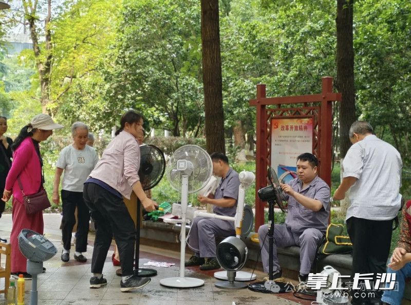 物业电工为业主清洁保养电风扇。