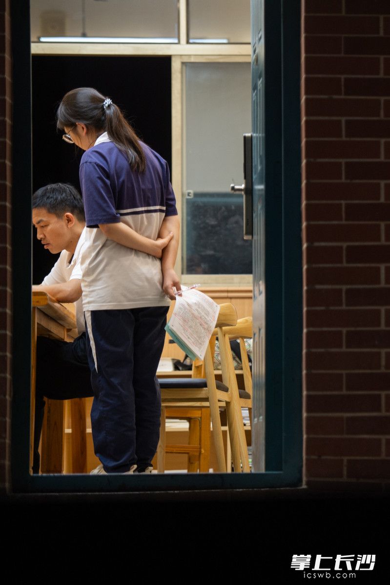 5月29日晚，长沙明德中学，任课老师邹伟光在办公室里为学生解答问题。