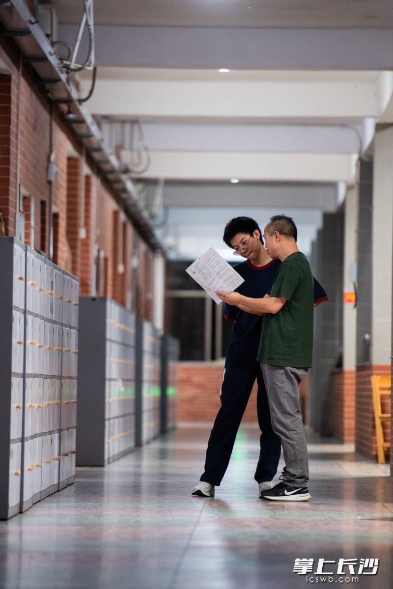 5月29日晚，长沙明德中学，任课老师罗召庆在走廊上为学生解答问题。