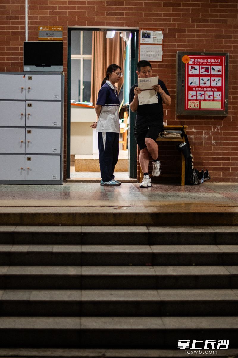 5月29日晚，长沙明德中学，任课老师尹爱国倚靠在教室门口上上为学生解答问题。