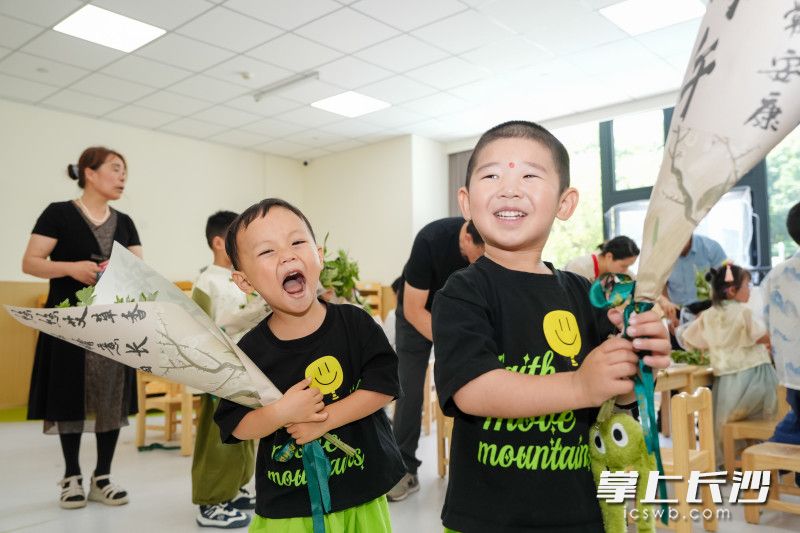 5月30日，雨花区教育局绿地城市幼儿园，端午六一双节游园会，两位小朋友抱着DIY 的艾草花束笑开了花。 长沙晚报全媒体记者 邹麟 通讯员 蒋丽梅 摄