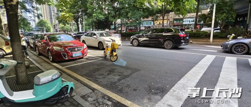 开福区北辰三角洲的一小区车库出口与车行道相连的道路上，一辆电动车横停在马路中央。