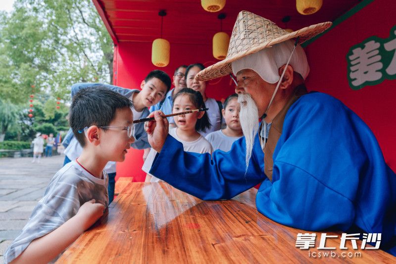 “姜太公”为游客“点额画虎”，再现古老的祈福仪式。