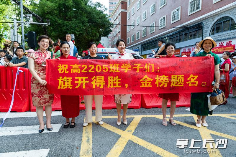 高考第一天，长沙市一中考点外聚集了很多家长，他们都带着道具满怀期待前来为考生加油鼓劲。均为长沙晚报全媒体记者 董阳 摄