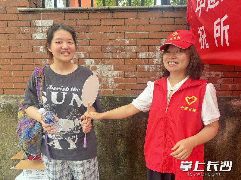 志愿者为考生送上水和扇子。中建五局供图