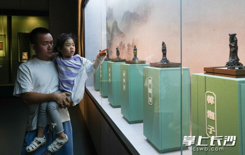 一位家长带着小孩观看《潇湘石韵——湖南博物院藏石雕精品展》展览。