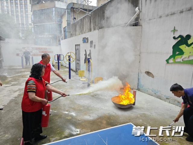 居民轮流使用干粉灭火器扑灭油盆火。