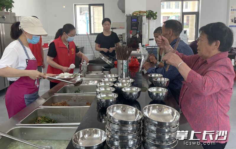 在宁乡市候旨亭社区老年助餐服务点，食堂工作人员热情地为老人们添饭加菜。均为长沙晚报全媒体记者 张禹 通讯员 孙新明 摄影报道