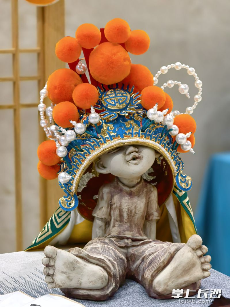 泥塑孩童“故意”把眼睛遮住，圆圆的脸蛋，撅着的小嘴歪着头，充满了俏皮与搞怪。