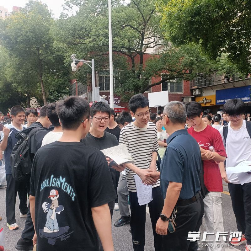 长沙市实验中学党委书记肖建军把考生送到考场，握个手传递满满的祝福。