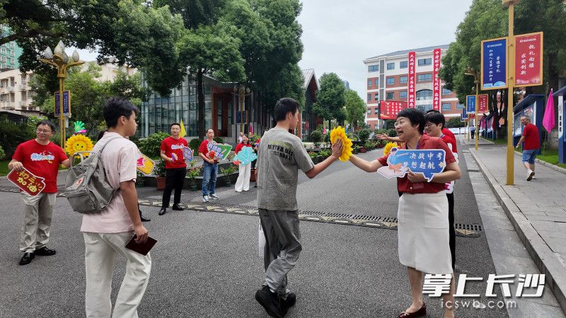 老师们手持向日葵组成助考加油团，与考生们击掌鼓劲。