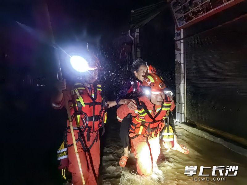 消防员袁鹏将老人背出被洪水围困的房子，在齐腰深的水中徒步前行，将老人安全转移。 长沙晚报通讯员 冯运文 供图