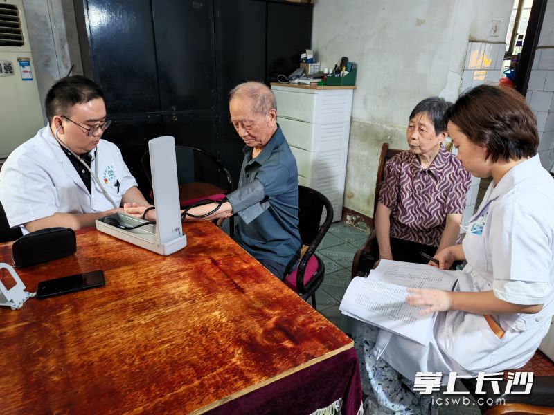 家庭医生尹君华正在为彭爷爷测量血压。