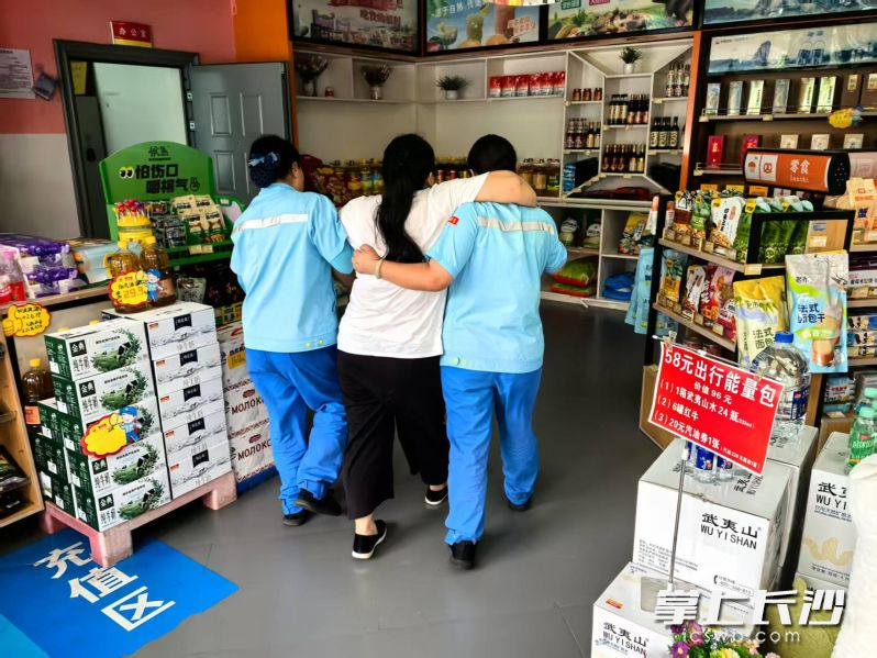 加油站员工将车主搀扶到阴凉处休息。