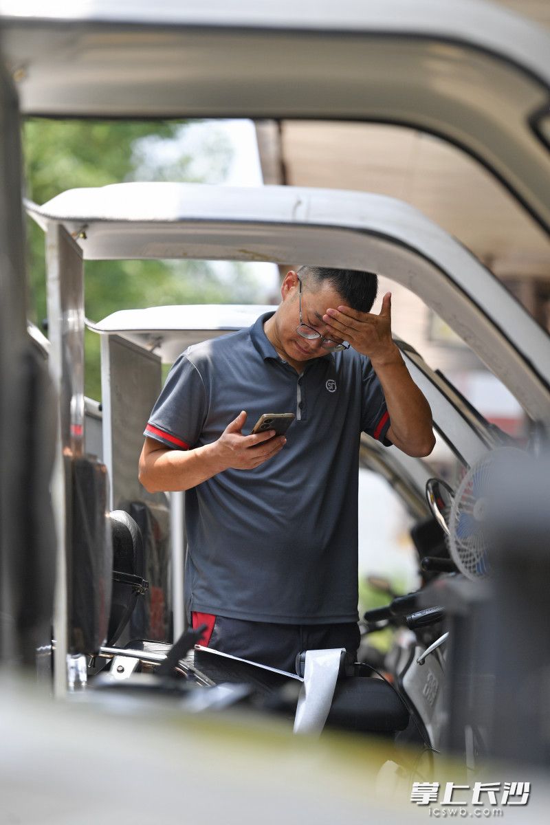 炎炎烈日下，顺丰速运快递小哥胡林海一边联系客户一边擦拭额头的汗珠。