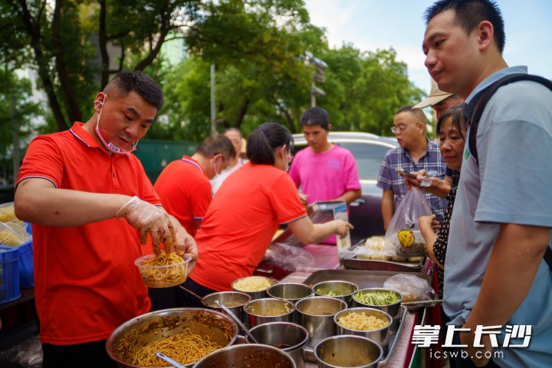 9日下午，潇湘华天大酒店南侧通道已人头攒动，酱香浓郁的鸭掌、猪脚，爽滑地道的安乡凉面，刚一出摊便被闻讯而来的市民团团围住。均由全媒体记者 邓迪 摄
