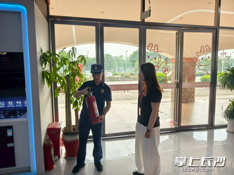 消防宣传员向商户讲解灭火器的使用方法，进行消防宣传。长沙晚报通讯员 汤淑 摄