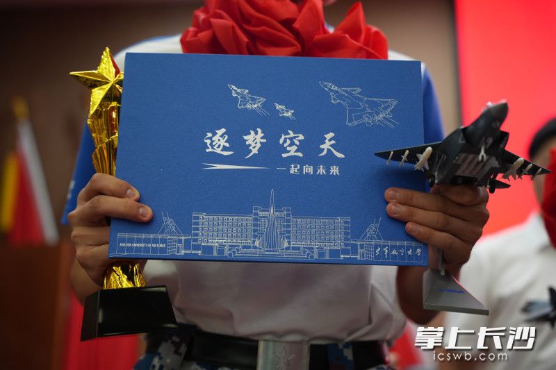 深蓝色的空军飞行学员录取通知书和“空军飞行学员之家”奖杯，代表沉甸甸的荣誉和使命。