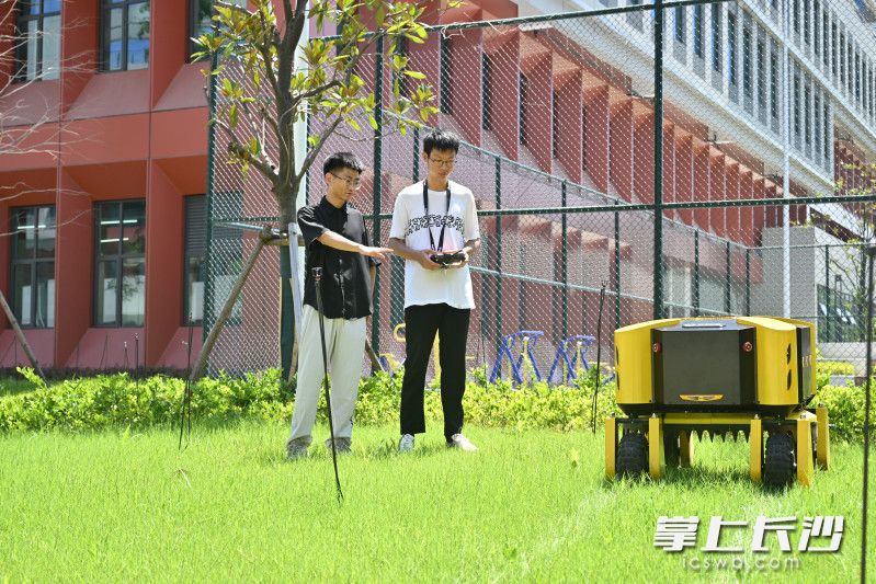 在岳麓山实验室，陈旭阳（左）与创业团队的小伙伴们一起测试除草机。  长沙晚报全媒体记者 余劭劼 摄