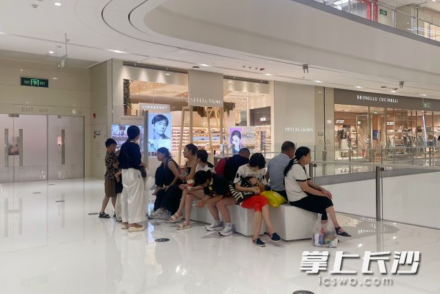 商场中人流如织，不少市民在长椅上休息纳凉。