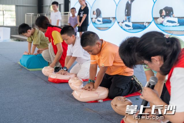 在几名志愿者指导下，孩子们轮流上阵练习按压手法和人工呼吸技巧。