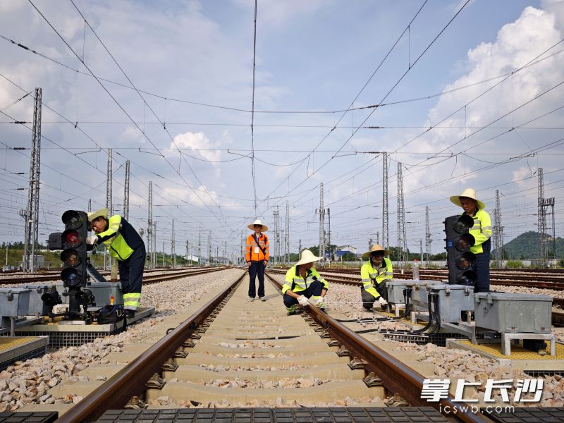铁路信号工们顾不上中午太阳的毒辣，抓紧时间对信号设备进行检修。