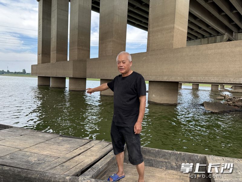 廖练刚指着小伙被水冲到的桥墩，讲述当时情形。均为全媒体记者 李金 摄影
