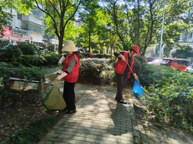 “金姐桂哥”志愿者们手持夹子，认真清理着绿化带里的白色垃圾。