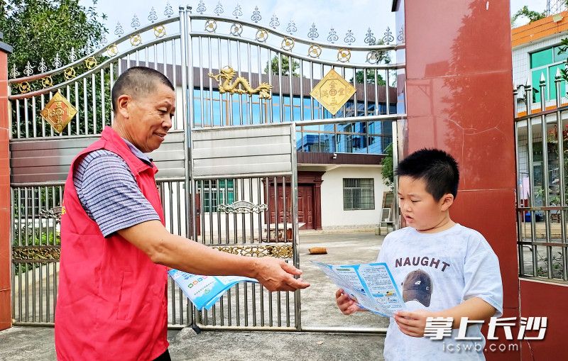 一名组长在向小朋友发放安全度暑假宣传单。