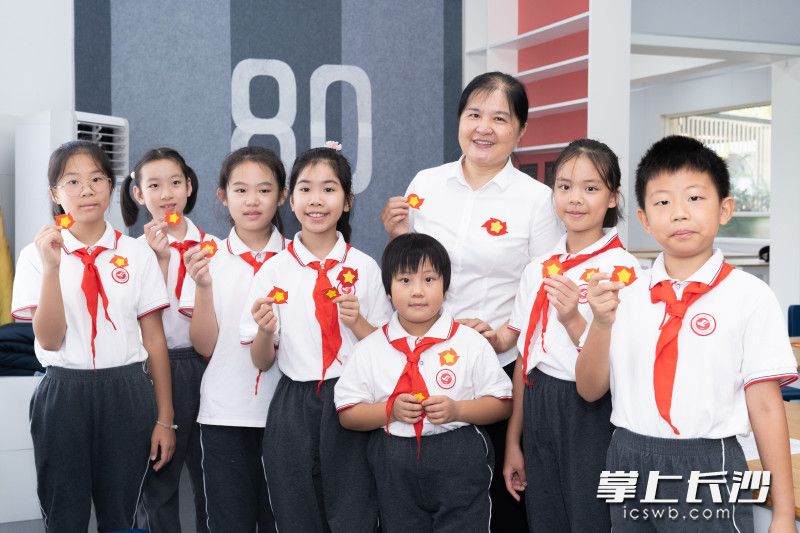 砂子塘小学党总支书记李臻（中）跟学生们一起做胜利花。