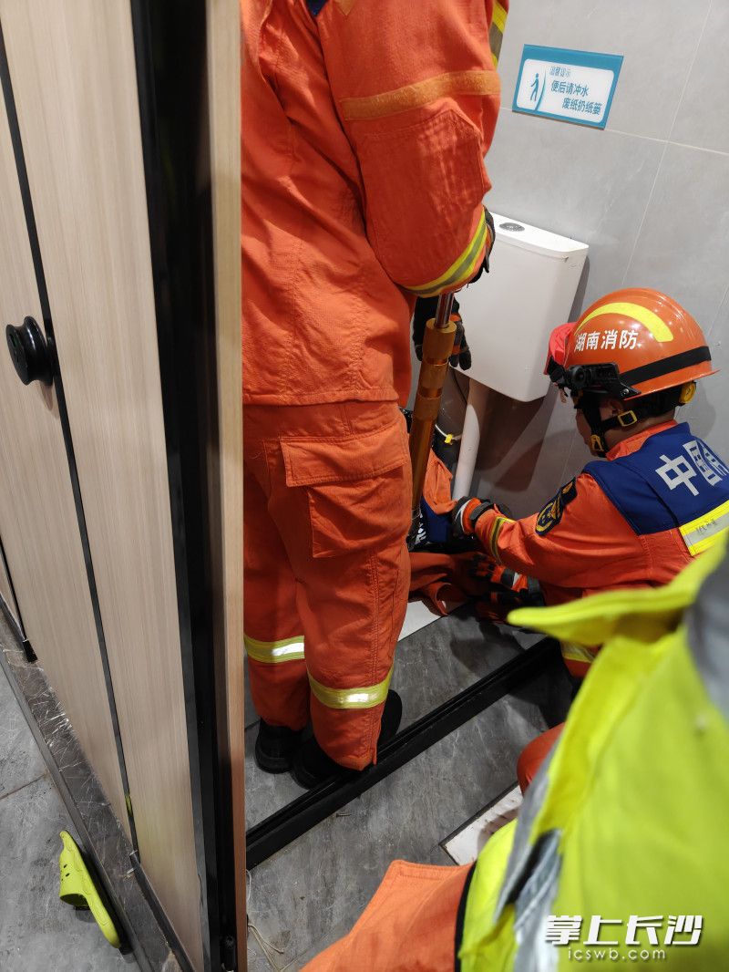 消防员正在破拆便池营救被卡手子。 长沙晚报通讯员 王磊 摄