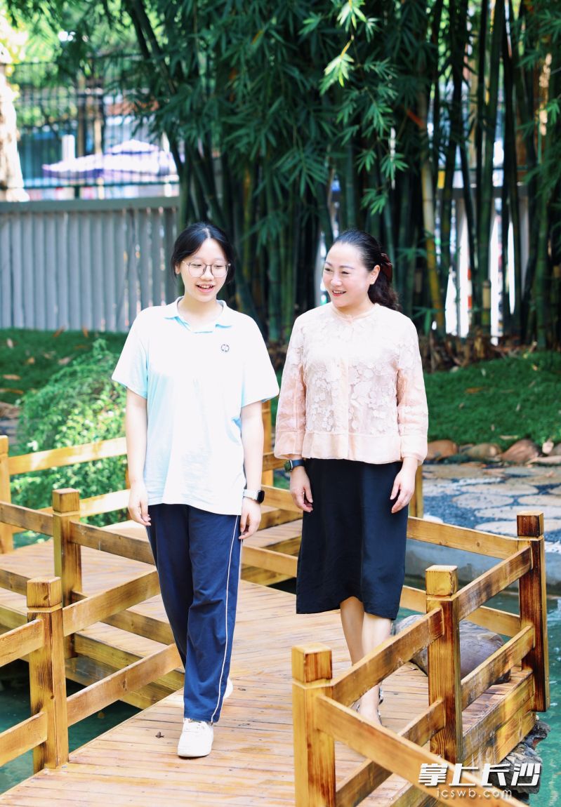 羿莎与学生漫步在校园，将自身求学时汲取的温暖与智慧，转化为滋养学生成长的养分。