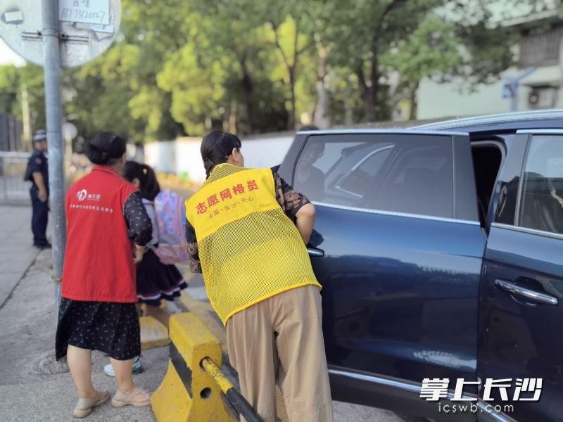 志愿者叮嘱接送孩子的家长即停即走。
