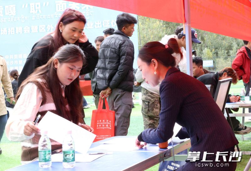 求职者在长沙企业展位前填写登记表。