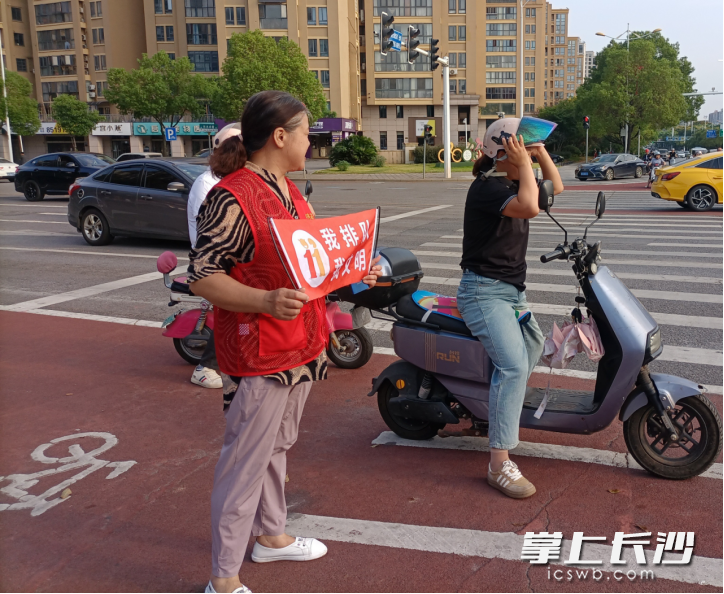 志愿者劝导戴盔骑行。 均为通讯员供图