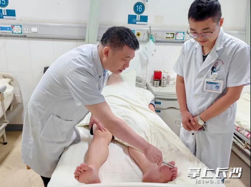 在长沙工作、新疆参保的张先生因工伤在湖南省职业病防治院接受治疗，医护人员查看其恢复情况。