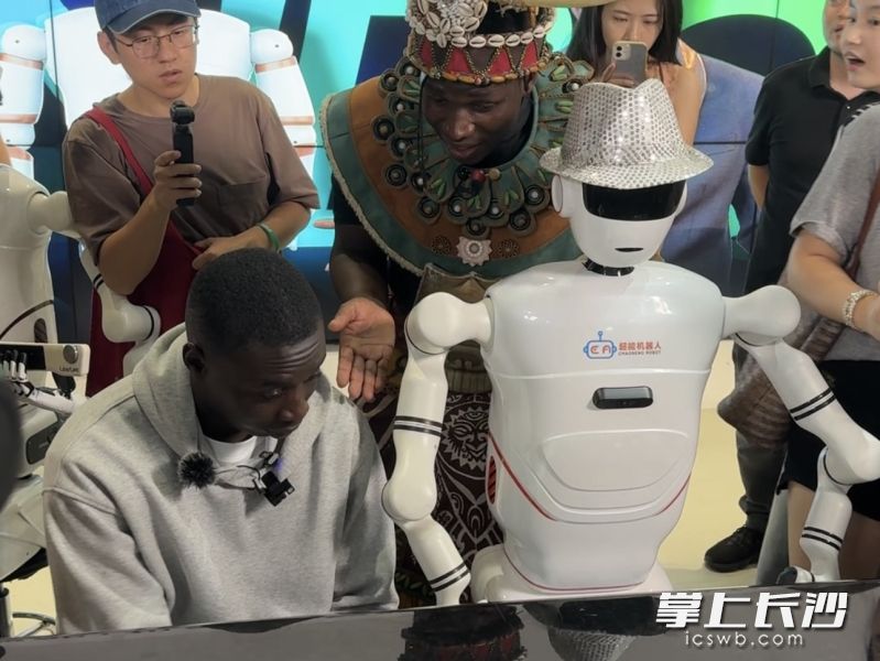 “无语哥”欣赏机器人乐队的演出，并参与互动。 长沙晚报全媒体记者 张馨以 摄