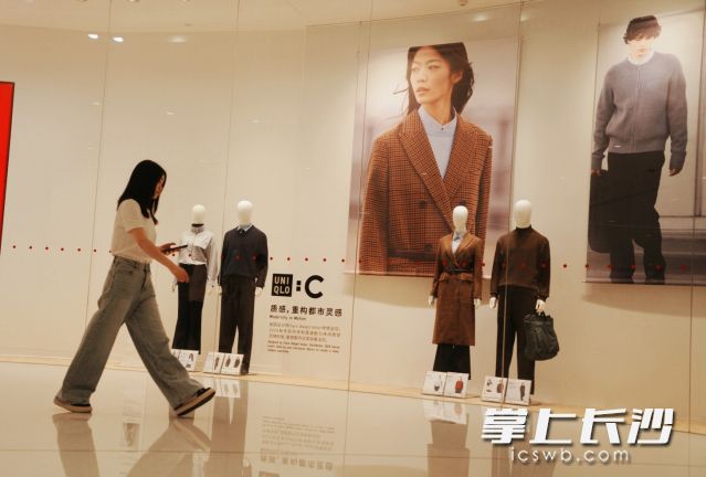 一位穿短袖的市民从展示秋冬装的橱窗经过。