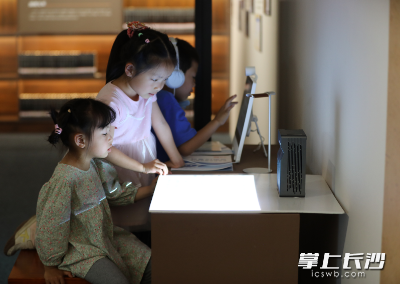 中小学生读者在长沙图书馆二楼展厅“书承文脉远 家国湖湘情”文献特展参与数字互动。