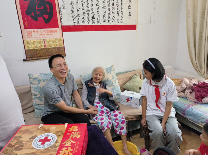 长沙县红十字志愿者们来到长沙县黄金塘社区百岁老人丁奶奶家中，将月饼等物资送到丁奶奶手中。
